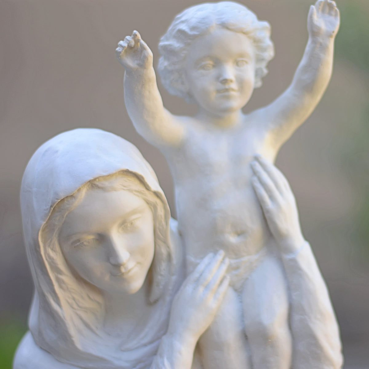 Visage de Marie et l'Enfant Jésus les bras levés, détail de la statue Notre Dame de France en résine blanche